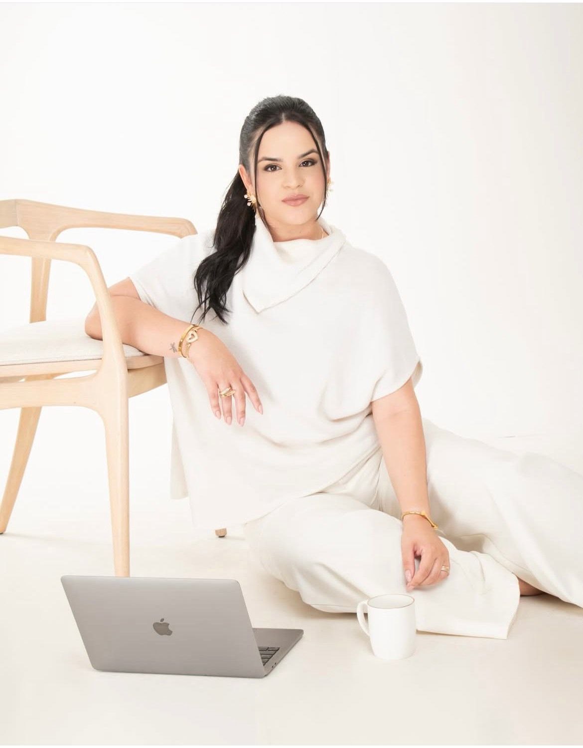 Clara Carlos, arquiteta, sentada no estúdio ao lado do notebook